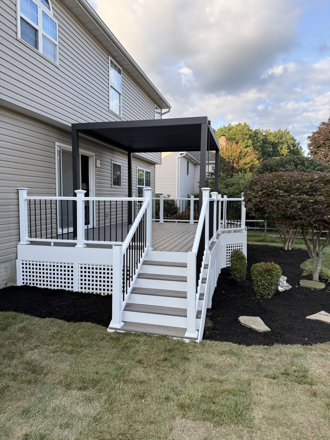 A finished composite deck with a pergola, white rails and lattice skirting