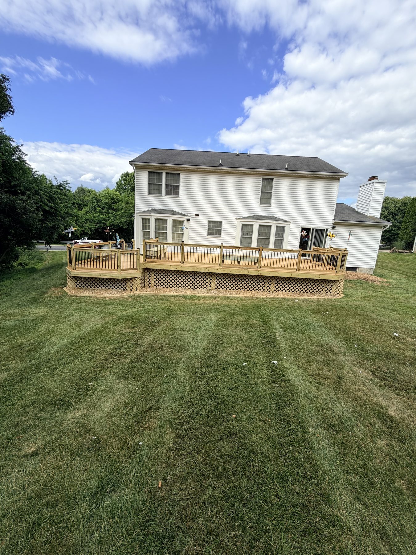 A finished wood deck with lattice skirting and a striped lawn